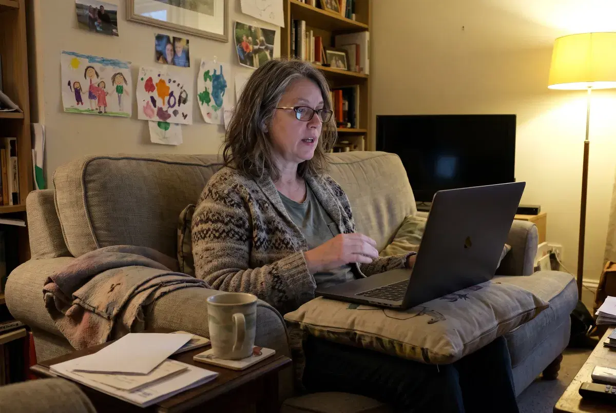 A woman taking a video interview on her laptop on the sofa in the evening