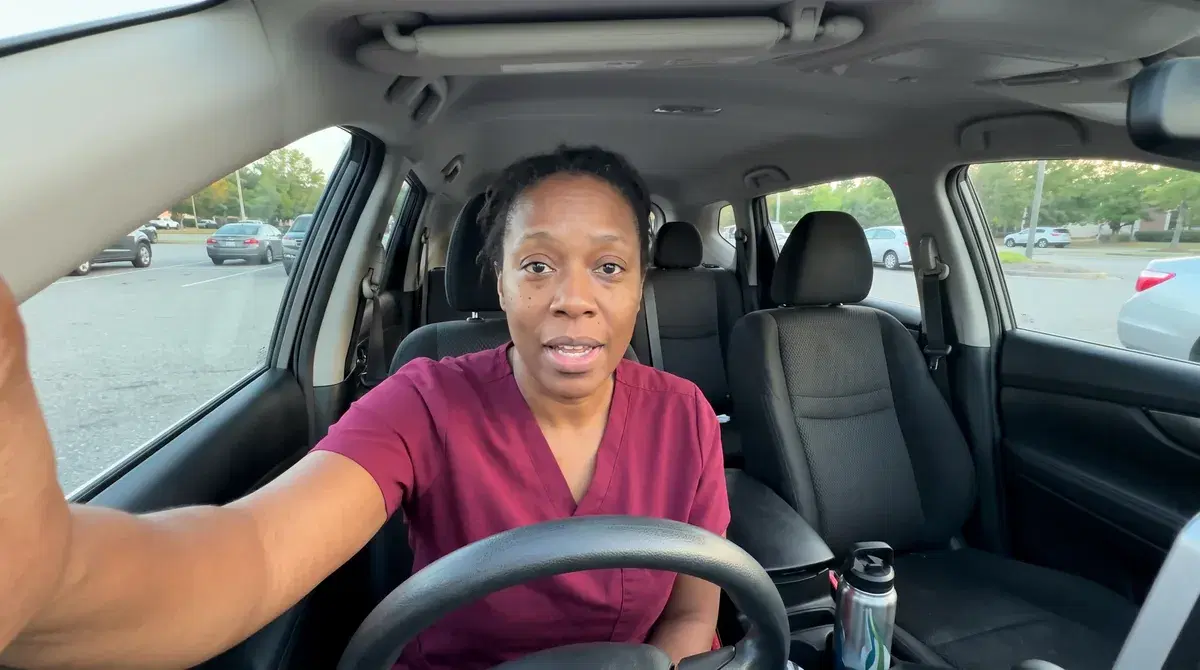 Denise, a home care aide applicant in scrubs, answering an interview question from her parked car after a shift